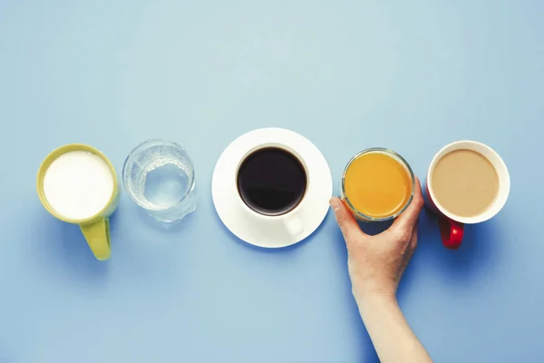 女性の手はオレンジのガラス グループの便利なドリンク ジュース オレンジ ジュース ミルクとコーヒー ブラック コーヒー 水だけ 青色の背景にヨーグルト — ストック写真