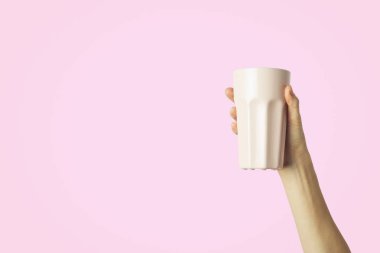 Mor bir fincan sıcak kahve veya çay hafif pembe bir arka plan üzerinde tutan el. Sıcak kahve veya çay ile kahvaltı konsepti.