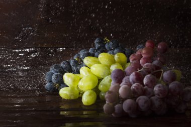Üzüm ahşap arka plan üzerinde birkaç çeşit su sıçramalarına ile. Taze meyve kavramı, yeni ürün.