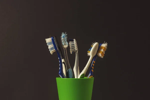 Muitas Escovas Dentes Uma Xícara Plástico Fundo Preto Conceito Mudança — Fotografia de Stock
