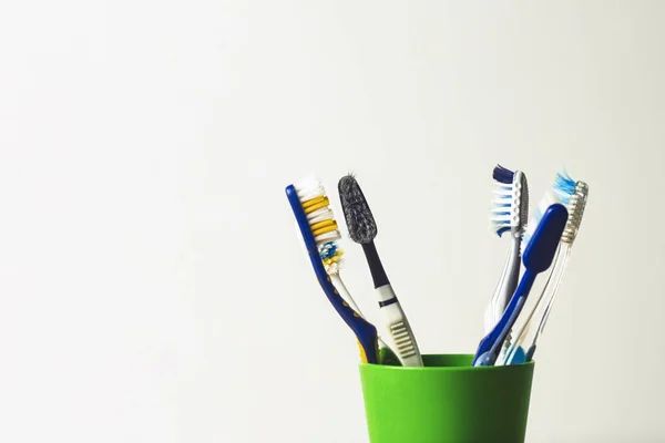 Muitas Escovas Dentes Uma Xícara Plástico Fundo Branco Conceito Mudança — Fotografia de Stock