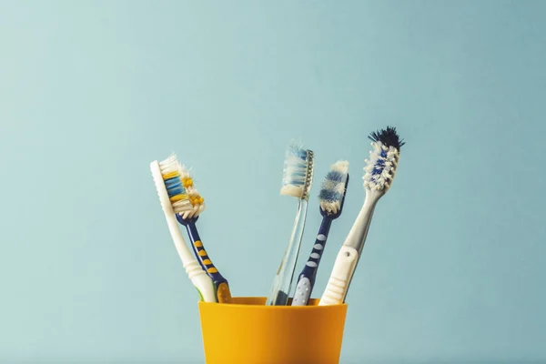 Muitas Escovas Dentes Uma Xícara Plástico Fundo Azul Conceito Mudança — Fotografia de Stock