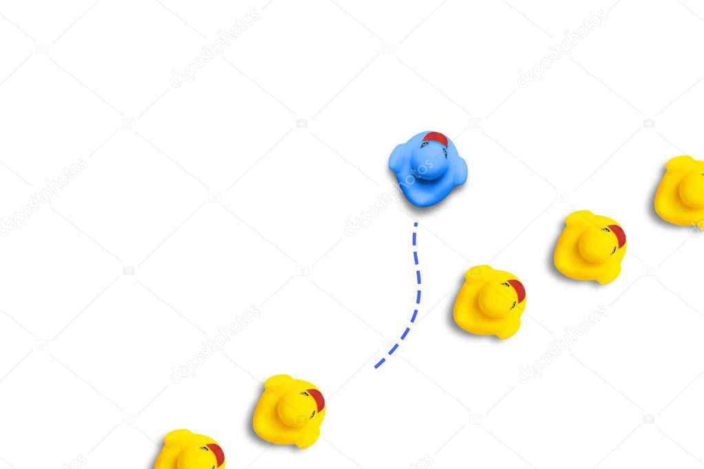 Group of yellow ducklings moves in one direction, but one blue duck swims in another direction. White background. The concept of innovative and creative business solutions. Flat lay, top view