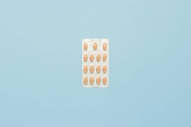 Plaka tabletler üzerinde mavi bir arka plan ile. Minimalizm. Ağrı kesiciler, antibiyotik, virüs tedavisi kavramı. Düz yatıyordu, en iyi görünümü