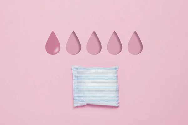 Feminine hygiene pad on a pink background. Concept of feminine hygiene during menstruation. Added drop mark, absorption level. One drop. Flat lay, top view