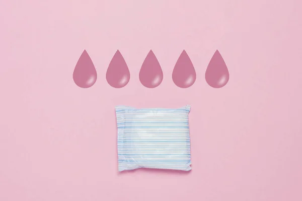 Feminine hygiene pad on a pink background. Concept of feminine hygiene during menstruation. Added drop mark, absorption level. five drops. Flat lay, top view