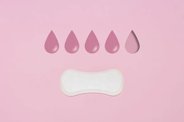 Feminine hygiene pad on a pink background. Concept of feminine hygiene during menstruation. Added drop mark, absorption level. four drops. Flat lay, top view