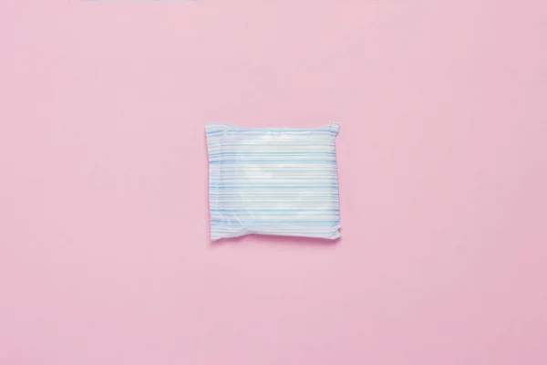 Feminine hygiene pad on a pink background. Concept of feminine hygiene during menstruation. Flat lay, top view