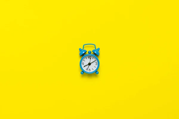 黄色の背景に青の目覚まし時計 昼と夜の概念 時間管理 昼と夜 ミニマリズムのスケジュール フラット横たわっていた トップ ビュー — ストック写真