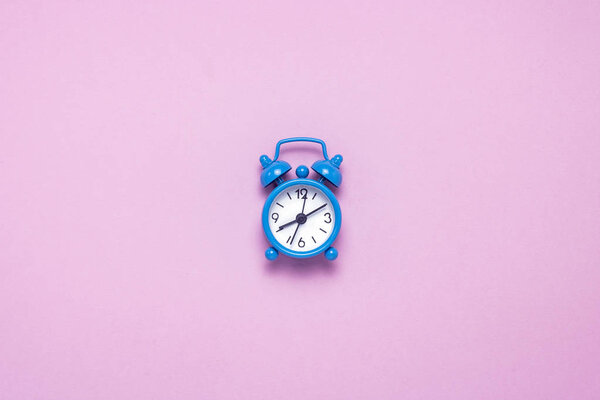 Blue alarm clock on a pink background. Concept day and night, time management, planning, schedule of day and night, minimalism. Flat lay, top view