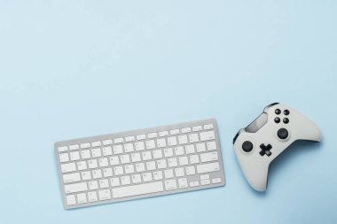 Klavye ve gamepad üzerinde mavi bir arka plan. Bilgisayar oyunları, eğlence, oyun, eğlence kavramı. Düz yatıyordu, en iyi görünümü
