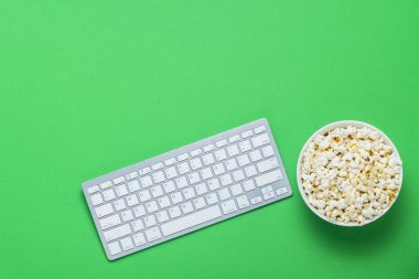 Klavye ve yeşil bir arka plan üzerinde patlamış mısır ile kase. Film izlerken kavramı gösterir Tv programları, spor online. Düz yatıyordu, en iyi görünümü