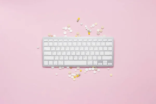 Keyboard, vitamins and pills on a pink background. The concept of buying vitamins, drugs, pills on the Internet, order via the Internet. Flat lay, top view