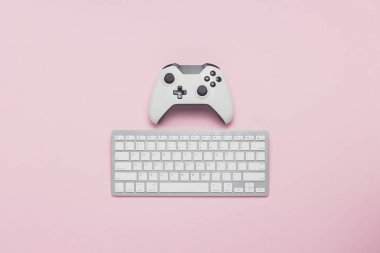 Beyaz gamepad ve pembe bir arka plan üzerinde klavye. Oyun taktikleri. Konsol ve Pc, bilgisayar oyunları kavramı oyunu. Düz yatıyordu, en iyi görünümü