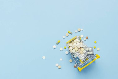Mavi bir arka plan haplarla dolu marketten alışveriş sepeti. Satın alınan ve tıbbi hazırlıklar, internette satın alabilirsiniz. Düz yatıyordu, en iyi görünümü
