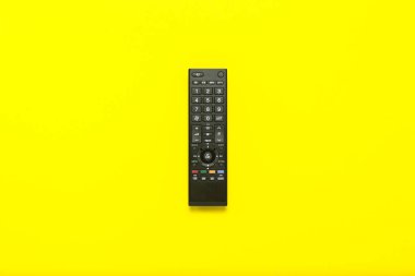 Sarı bir arka plan üzerinde siyah uzaktan kumanda. Televizyon, film, Tv şovları, spor kavramı. Düz yatıyordu, en iyi görünümü