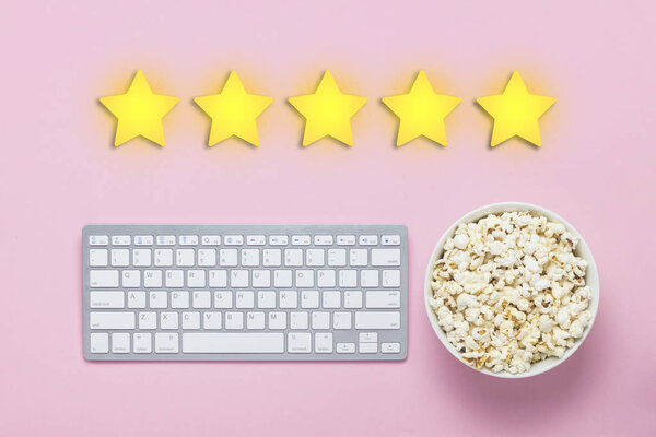 Bowl of popcorn, keyboard on a pink background. Added five stars rating. Reputation. Concept of watching movies, TV shows, sports. Audit and evaluation. Flat lay, top view