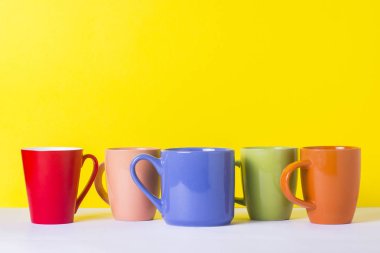 Bir sürü kahve veya çay sarı bir arka plan üzerinde renkli bardak. Bir dostu firma, büyük bir aile, bir fincan çay ya da kahve için toplantı arkadaşlar kavramı