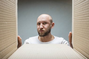 Ciddi bir yüz olan bir adam bir Aç kutusuna arıyor. İç görünüm. Kavram alınan bir parsel, sipariş, Internet mogazin, malların teslim, söylememiştir, zavallı teslim