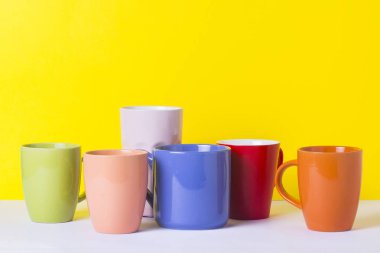 Bir sürü kahve veya çay sarı bir arka plan üzerinde renkli bardak. Bir dostu firma, büyük bir aile, bir fincan çay ya da kahve için toplantı arkadaşlar kavramı