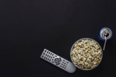 Bir kase patlamış mısır, bir Tv Uzaktan kumanda, içki siyah bir zemin üzerine bir kutu. Tarassut Tv, film, Tv dizisi, spor, kavramı gösterir. Düz yatıyordu, en iyi görünümü