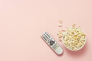 Patlamış mısır ve bir Tv bir pembe uzak bir kase. Tarassut Tv, film, Tv dizisi, spor, kavramı gösterir. Düz yatıyordu, en iyi görünümü