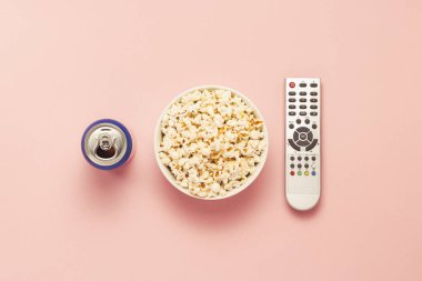 Bir kase patlamış mısır, bir Tv Uzaktan kumanda, pembe bir arka plan üzerinde içki bir kavanoz. Tarassut Tv, film, Tv dizisi, spor, kavramı gösterir. Düz yatıyordu, en iyi görünümü