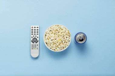 Bir kase patlamış mısır, bir Tv Uzaktan, bir kutu mavi bir arka plan üzerinde bir içkiyle. Tarassut Tv, film, Tv dizisi, spor, kavramı gösterir. Düz yatıyordu, en iyi görünümü