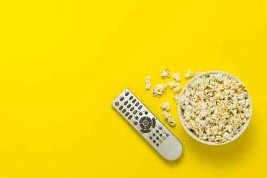 Patlamış mısır ve Tv sarı bir arka plan üzerinde uzak bir kase. Tarassut Tv, film, Tv dizisi, spor, kavramı gösterir. Düz yatıyordu, en iyi görünümü