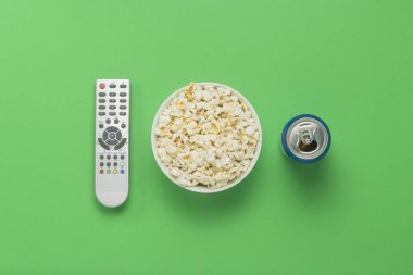Bir kase patlamış mısır, bir Tv Uzaktan, bir kutu yeşil bir arka plan üzerinde bir içkiyle. Tarassut Tv, film, Tv dizisi, spor, kavramı boş olarak gösterir. Düz yatıyordu, en iyi görünümü
