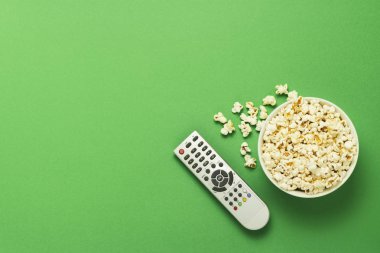 Bir kase patlamış mısır ve yeşil bir arka plan üzerinde uzak bir Tv. Tarassut Tv, film, Tv dizisi, spor, kavramı gösterir. Düz yatıyordu, en iyi görünümü