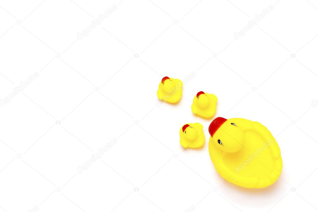 Rubber toy of yellow color Mama duck and small ducklings on a white background. The concept of maternal care and love for children. Flat lay, top view.