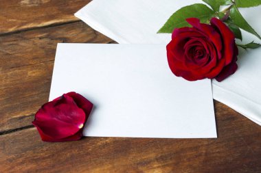 Kırmızı gül ve temiz kağıt yaprağının ahşap bir masa üzerinde. Düz yatıyordu, en iyi görünümü 