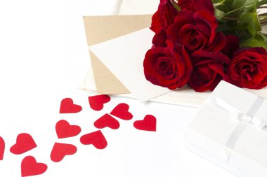 Buket kırmızı gül ve bir not, kırmızı kalpler olan bir zarf karton beyaz bir arka plan üzerinde yapılmış. Kavramı bir romantik hediye. Düğün Temalar.