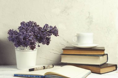 Leylak Beyaz bir dekoratif demet, kitaplar, açık günlük, beyaz fincan kahve beyaz taş zemin üzerine yığını.