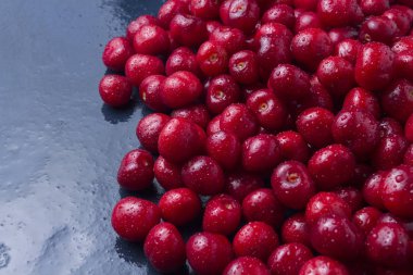 Taze kiraz su ve çiğ damlaları ile koyu mavi bir taş arka plan üzerinde aldı. Hasat kavramı. Düz yatıyordu, en iyi görünümü.