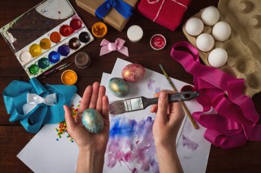 Mutlu paskalyalar. Paskalya boyama koyu ahşap bir masa bir arka plan üzerinde yumurta. Görünür eller vardır.