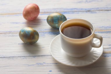 Paskalya yumurtaları ve kahve Beyaz ahşap bir masa üzerinde.