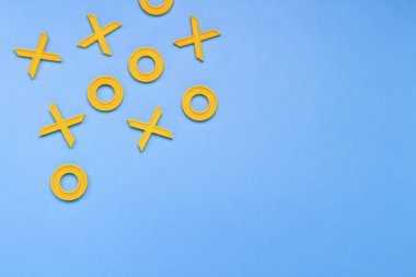 Sarı plastik haçlar ve mavi bir arka plan üzerinde üç taş oynamak için zeroches. Kavram Xo kazanmak Challenge. Gelişimsel oyun çocuklar için. Düz yatıyordu, en iyi görünümü.