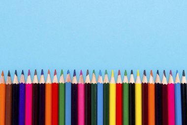 Renkli kalemler mavi bir arka plan üzerinde üst üste konmuş. Düz yatıyordu, en iyi görünümü.