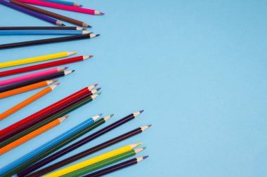 Mavi bir arka plan üzerinde renkli kalemler dağınık.