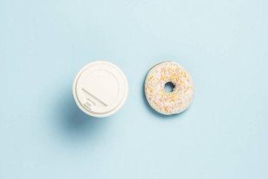 Taze lezzetli tatlı çörek ve kağıt bardak kahve veya çay üzerinde mavi bir arka plan ile. Fast food kavramı, ekmek, kahvaltı. Minimalizm. Düz yatıyordu, en iyi görünümü