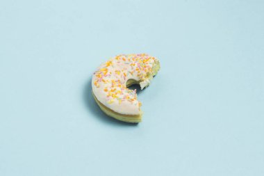 Isırıldı taze lezzetli tatlı çörek mavi bir arka plan üzerinde. Fast food kavramı, ekmek, kahvaltı. Minimalizm