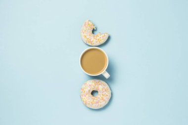 Fincan, kahve ya da çay süt ve taze lezzetli donuts mavi bir arka plan üzerinde beyaz. Fırın kavramı, taze hamur işleri, lezzetli breakfast, lokanta. Düz yatıyordu, en iyi görünümü