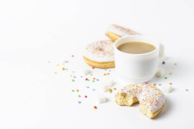 Fincan, kahve ya da çay süt ve taze lezzetli börekler, tatlı çok renkli dekoratif şeker beyaz bir arka plan üzerinde beyaz. Fırın kavramı, taze hamur işleri, leziz kahvaltı, fast food