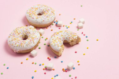 Taze lezzetli tatlı çörek, çok renkli dekoratif şekerleme, pembe bir arka plan üzerinde kesme şeker. Fırın kavramı, taze hamur işleri, leziz kahvaltı, fast food