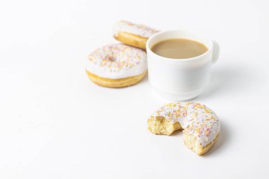 Fincan, kahve ya da çay süt ve taze lezzetli börekler, tatlı çok renkli dekoratif şeker beyaz bir arka plan üzerinde beyaz. Fırın kavramı, taze hamur işleri, leziz kahvaltı, fast food