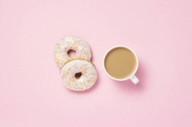 Beyaz fincan, kahve ya da çay süt ve taze lezzetli tatlı çörek üzerinde pembe bir arka plan ile. Fırın kavramı, taze hamur işleri, lezzetli breakfast, lokanta. Düz yatıyordu, en iyi görünümü