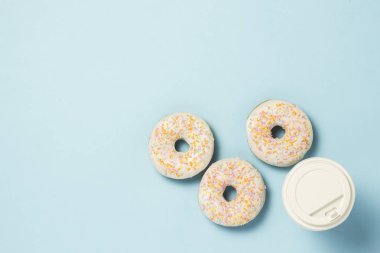 Taze lezzetli tatlı çörek ve bir kağıt bardak kahve veya çay mavi bir arka plan üzerinde. Fast food kavramı, ekmek, kahvaltı. Minimalizm. Düz yatıyordu, en iyi görünümü