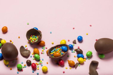 Kırık ve bütün çikolata Paskalya yumurtaları, çok renkli tatlılar, pembe bir arka plan. Çalı. Paskalya, Paskalya süsleri kutluyor kavramı. Düz yatıyordu, en iyi görünüm. Uzay kopyalayın. Mutlu Paskalya